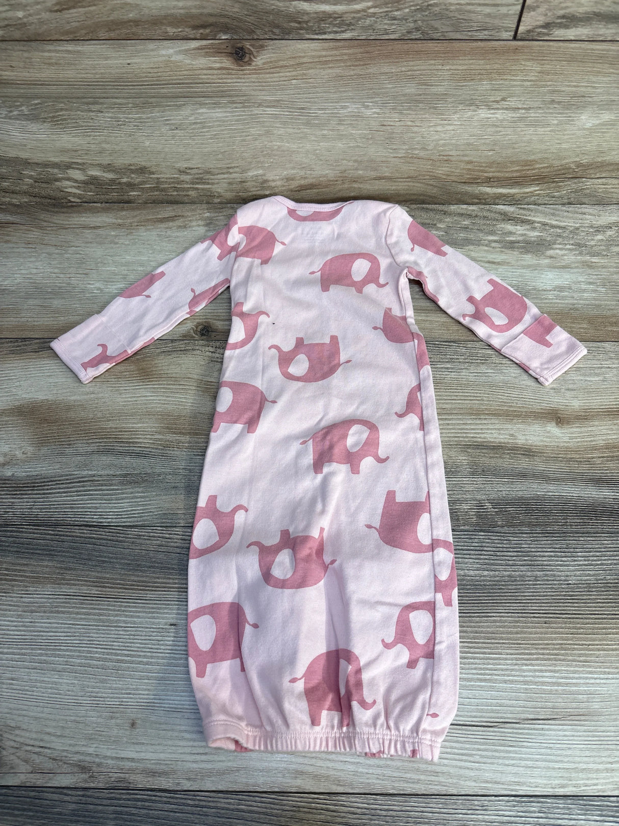 Pink elephant print baby onesie, long sleeve, soft cotton, for infants, laid on wood floor