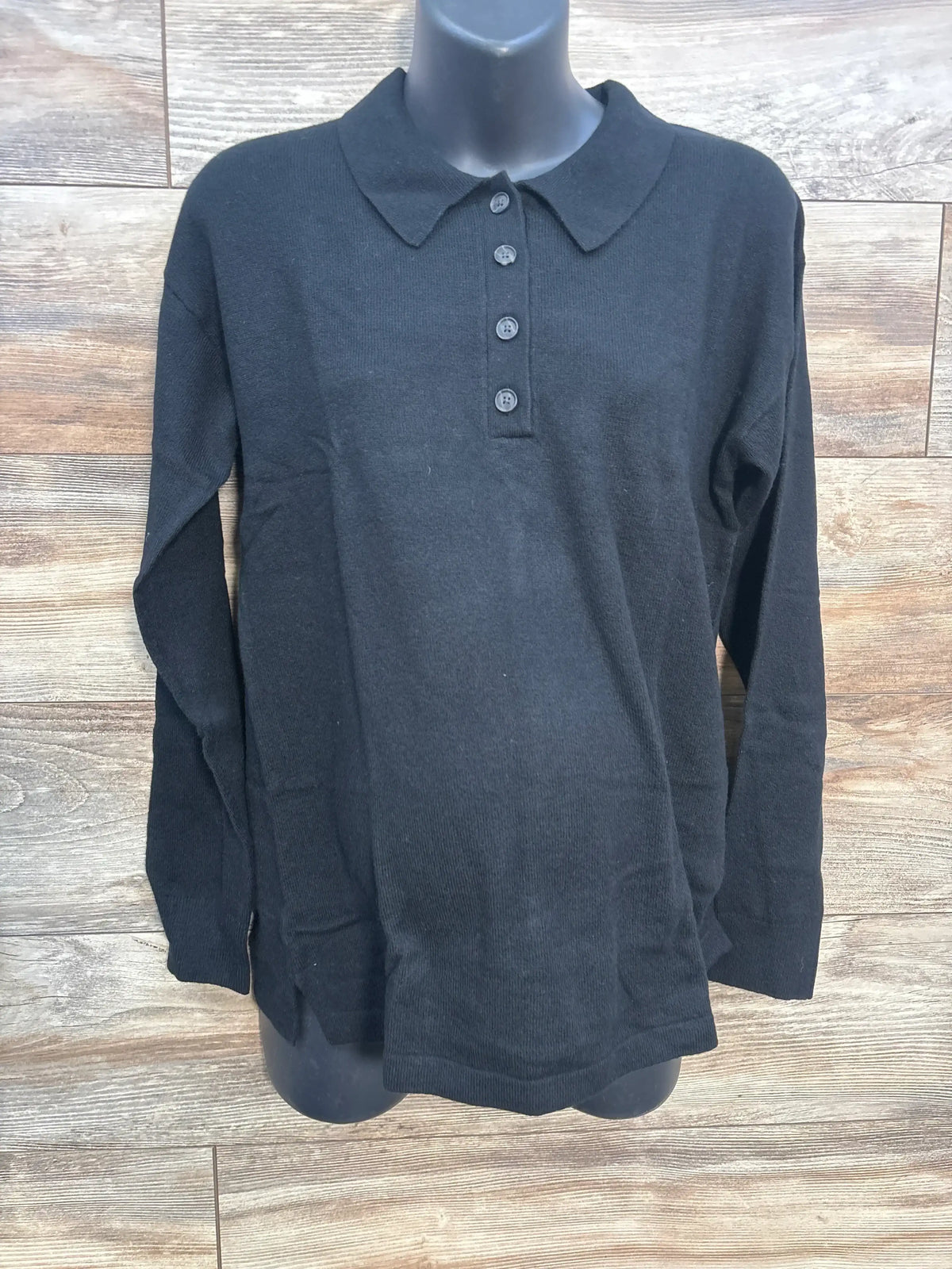 Black long sleeve knit polo shirt with four buttons on mannequin, wood background