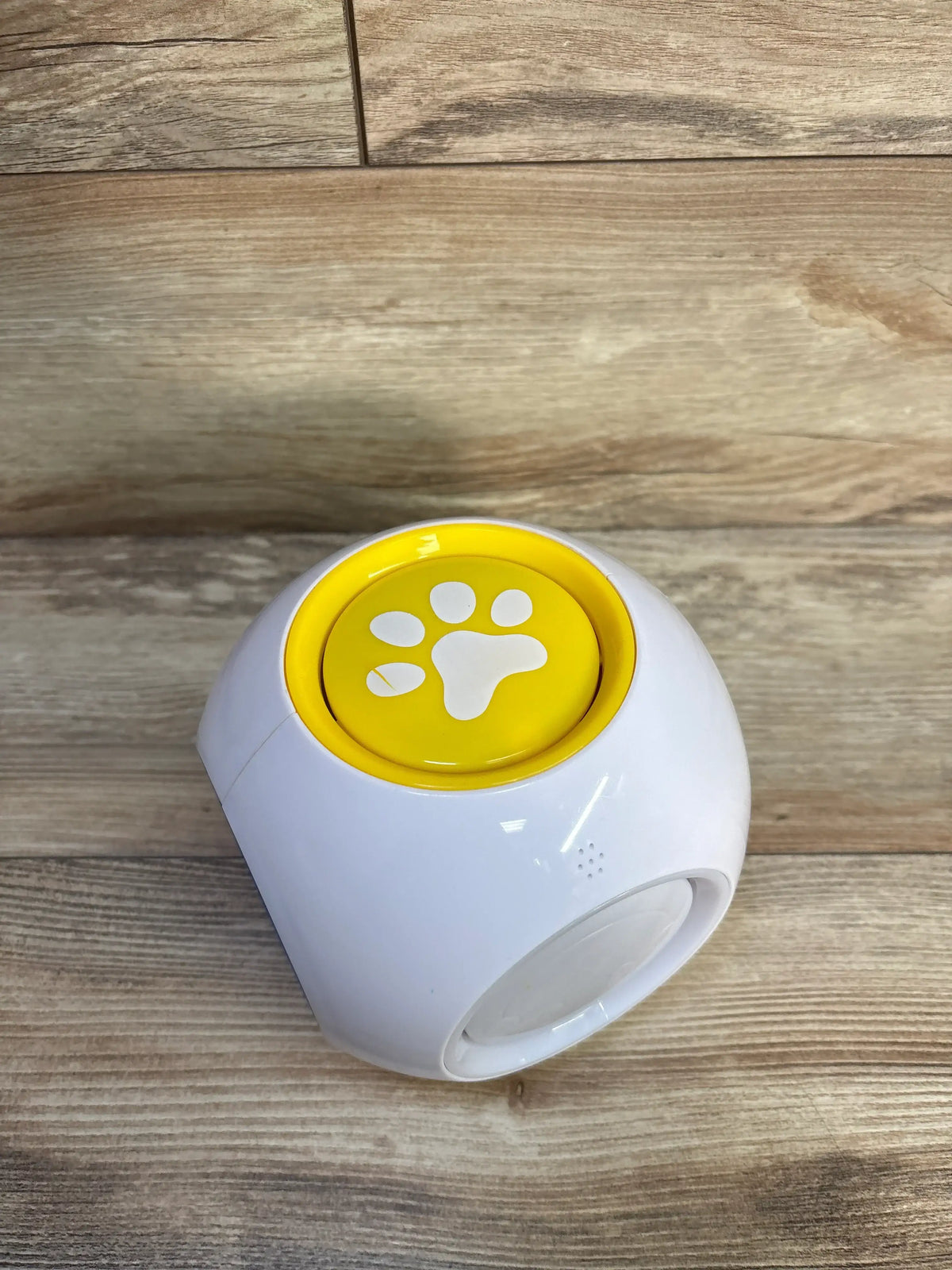 Angled view of Best Learning Learning Cube showcasing its yellow paw-print button and white body on a wood-grain surface