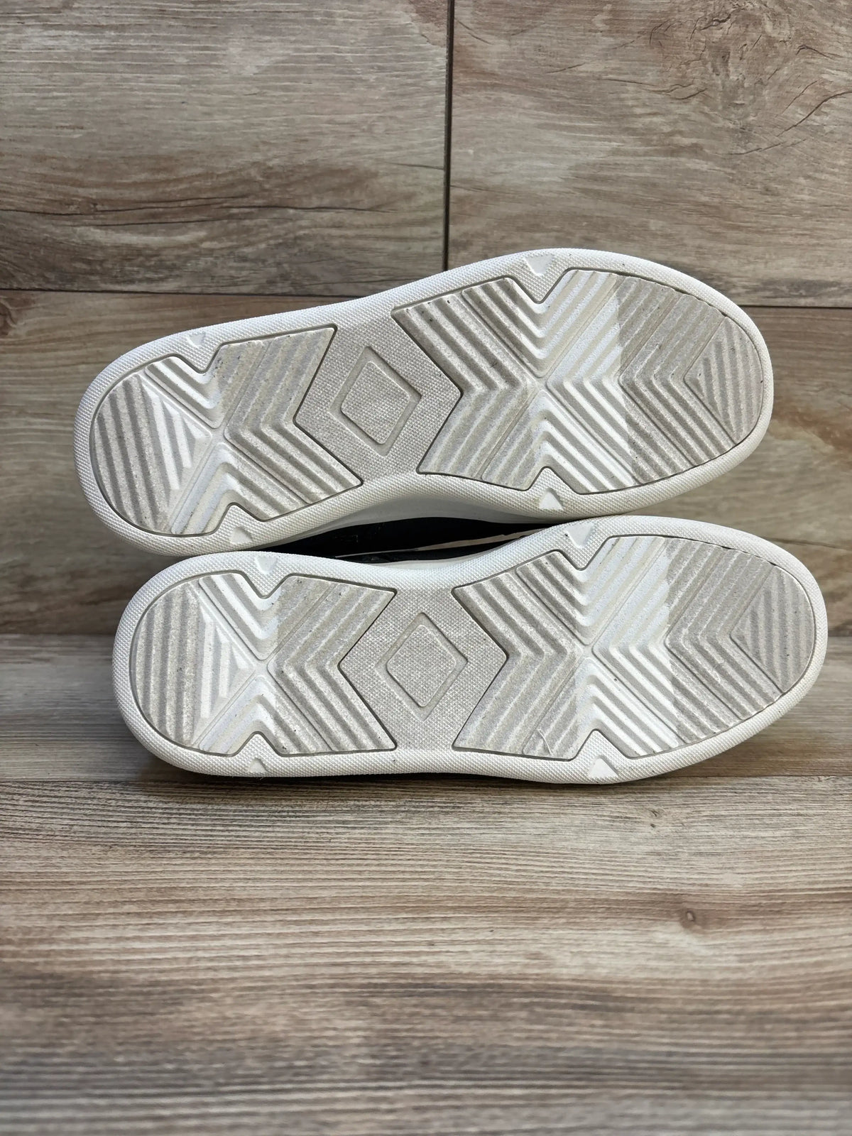 Bottom view of Art Class Geoff high-top sneakers size 5Y showing white soles with chevron tread and light wear on wood floor