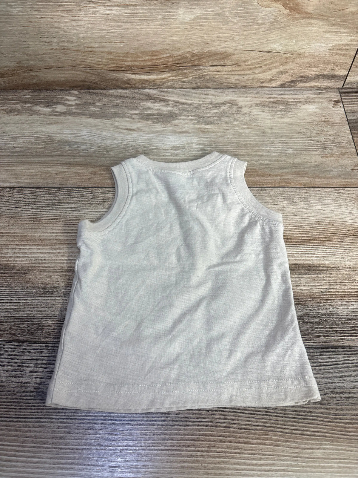 Front view of Carter’s beige tank top in size 3 months showcasing sleeveless design with a wood-grain background