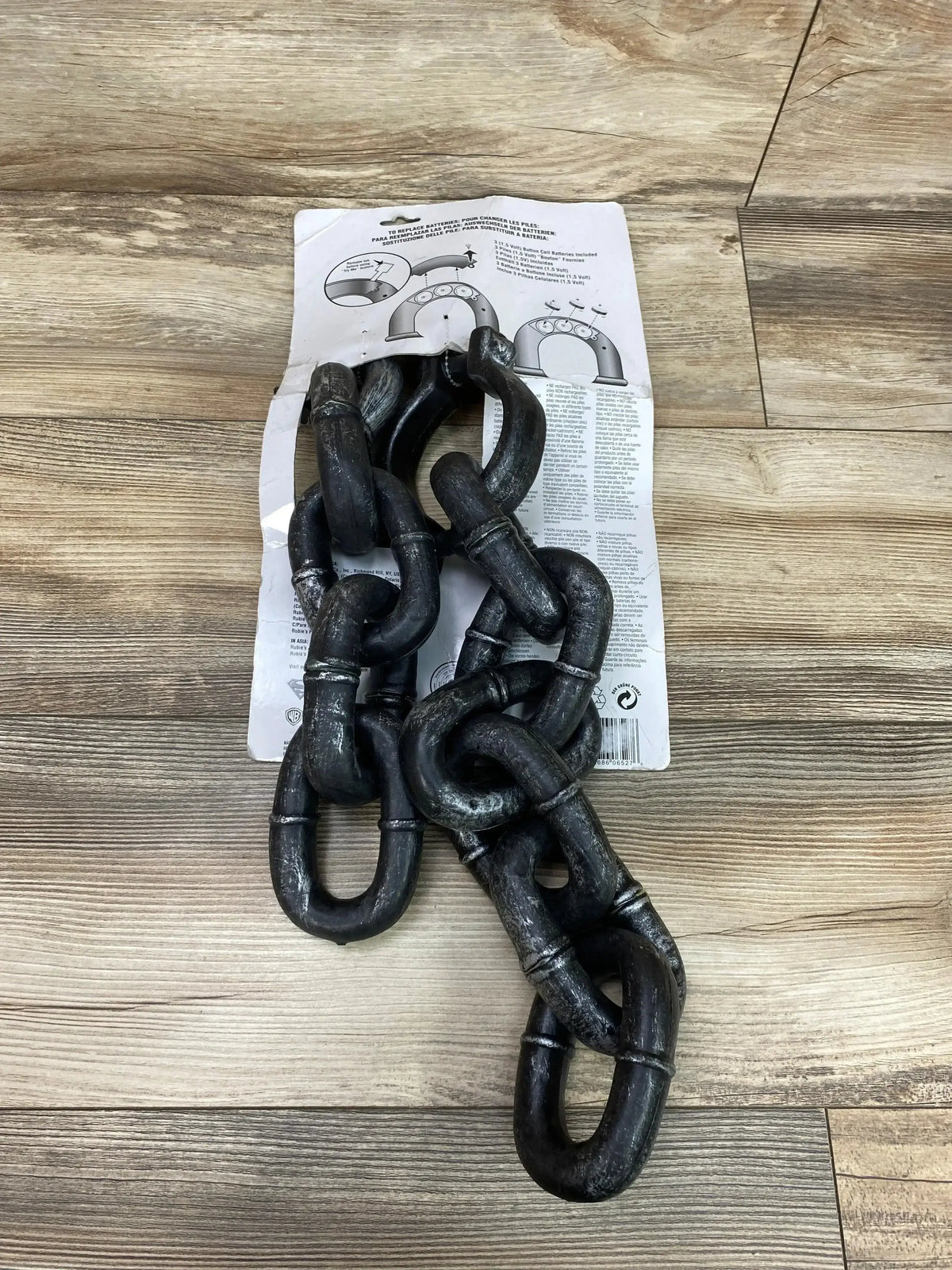 Top view of Rubies Break-Apart Shackles Chain showcasing black linked shackles on an instruction sheet over a wood floor