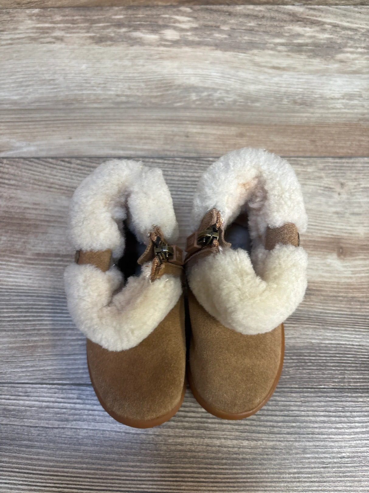 Toddler brown suede boots with white faux fur lining on wood background