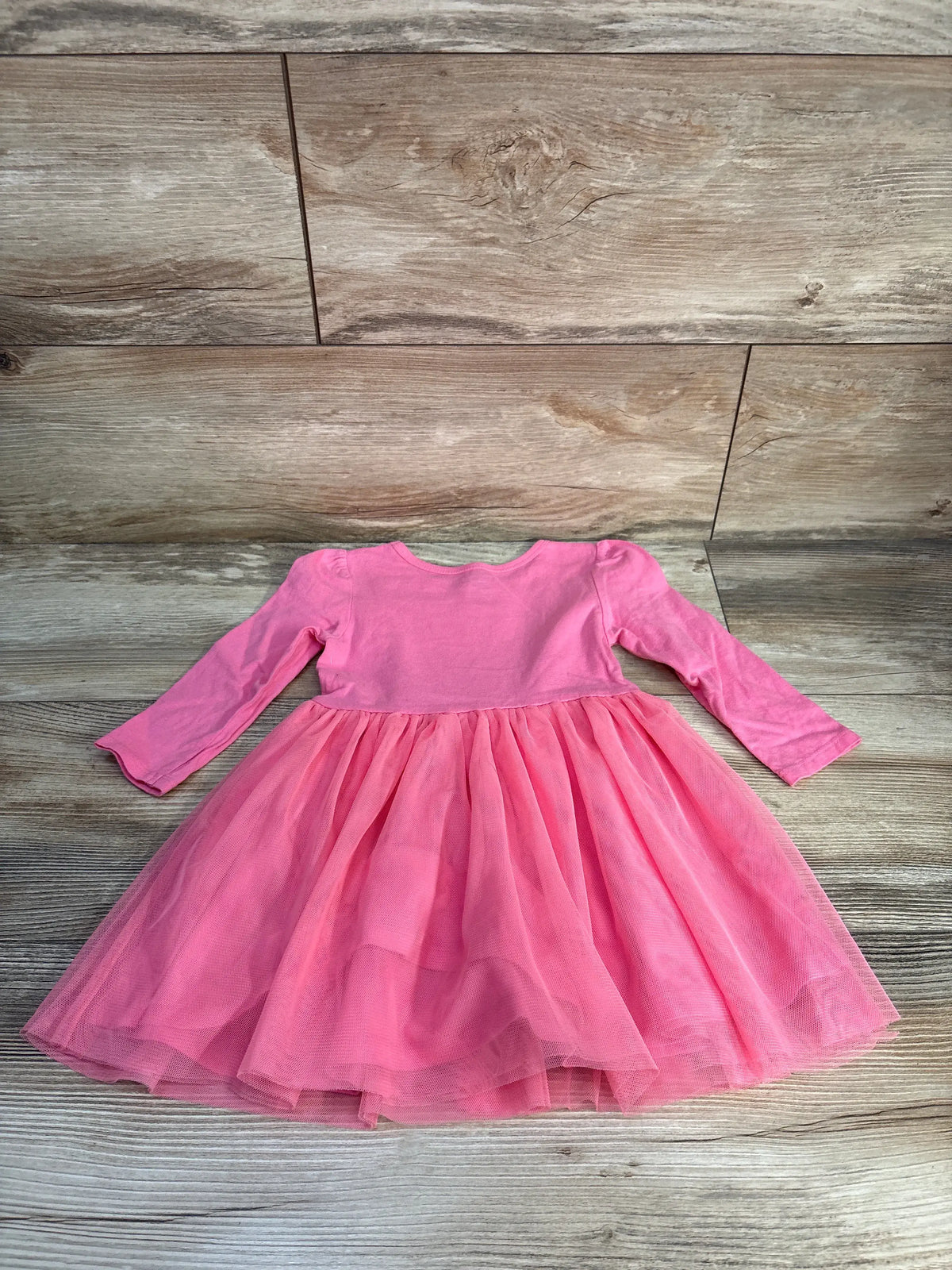 Front view of Carter’s Hello Kitty long sleeve tulle dress in pink showcasing its full tulle skirt and long sleeves on a wood floor
