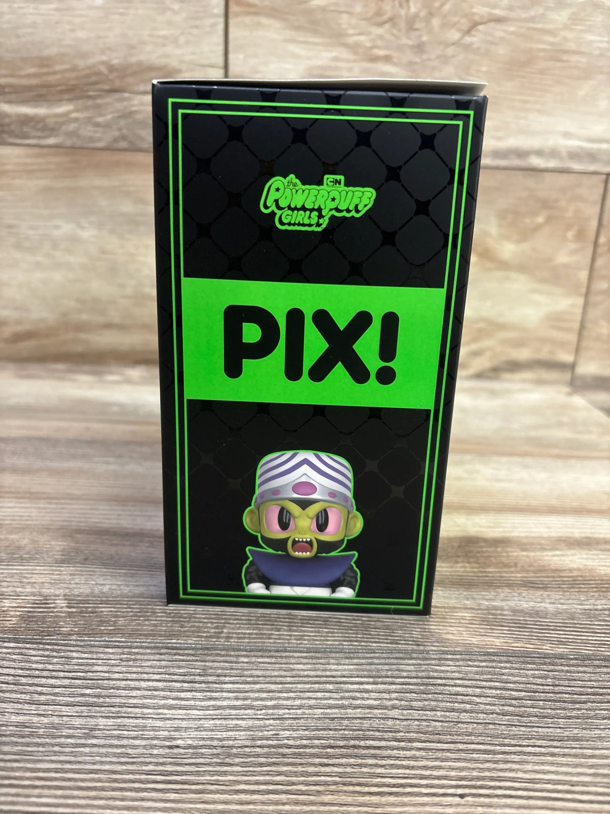 Front view of The Powerpuff Girls Mojo Jojo vinyl figure box showcasing green and black Pix packaging with a wood floor background
