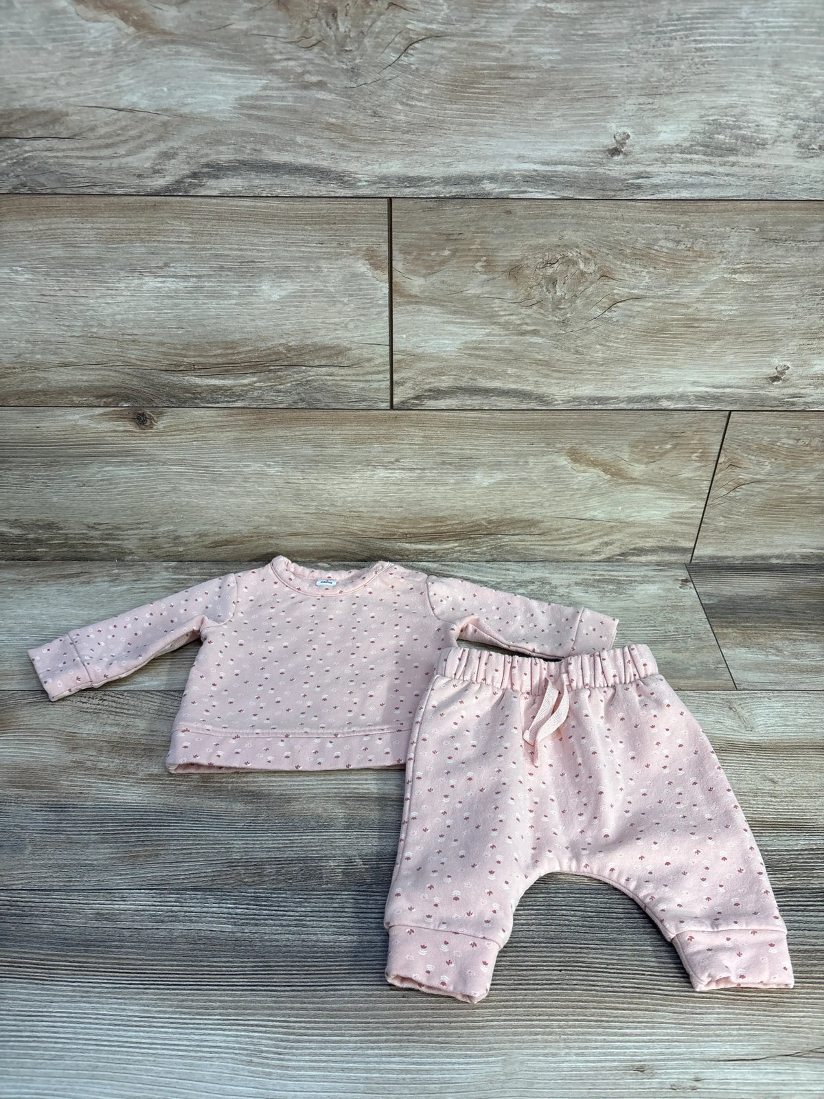 Flat lay of Nordstrom two-piece pink floral sweatshirt and pants set with a wood-grain background