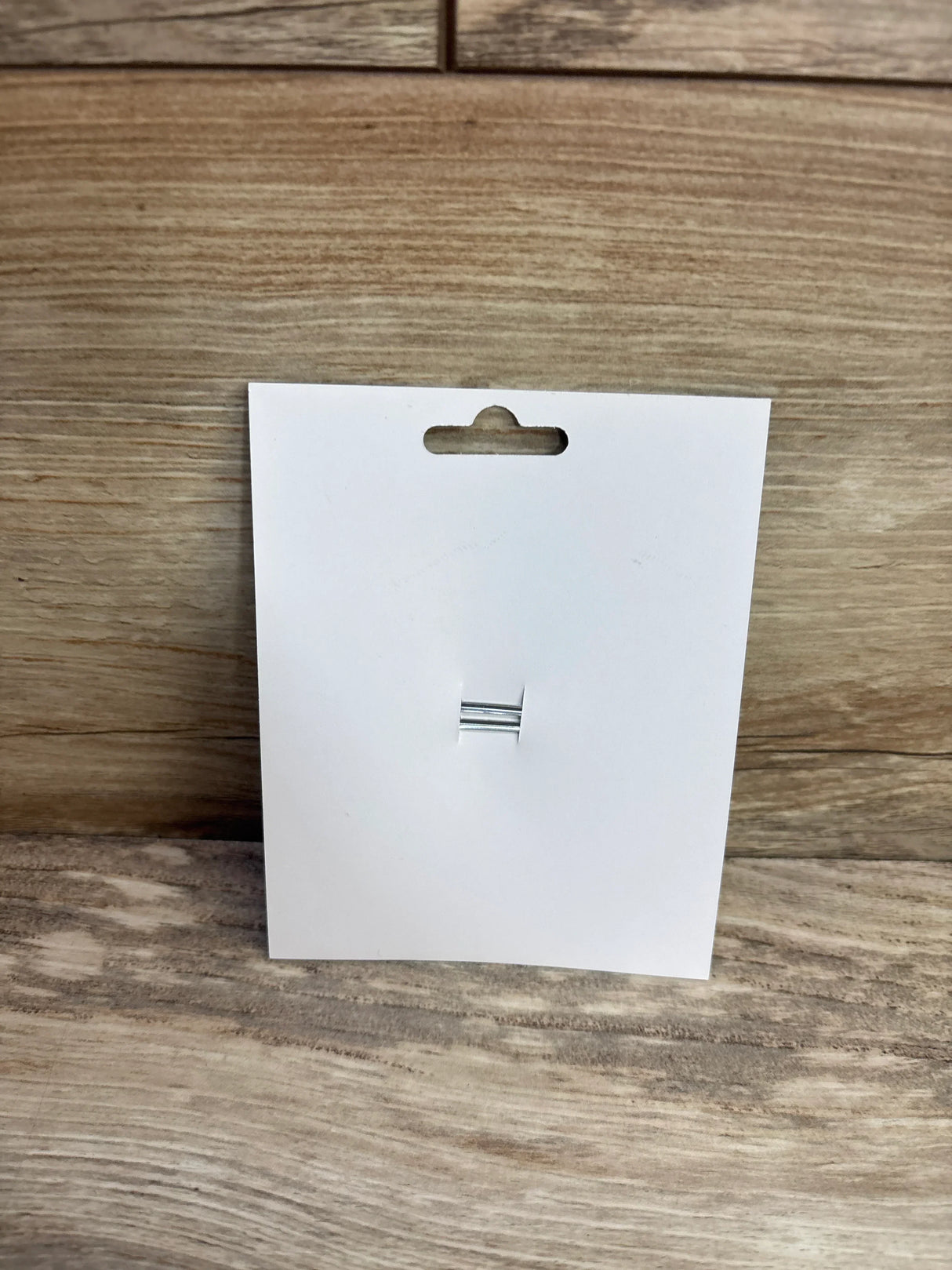 Front view of white display card for donut applique glitter hair bow showing attached silver two prong hair clip on wood background