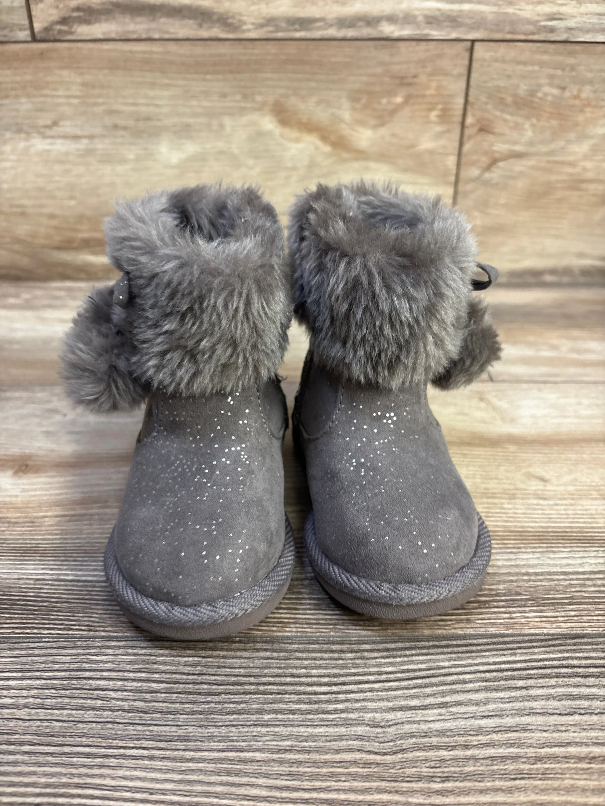 Front view of Jumping Beans toddler boots with grey suede, faux-fur cuff, and glitter speckles on wood background