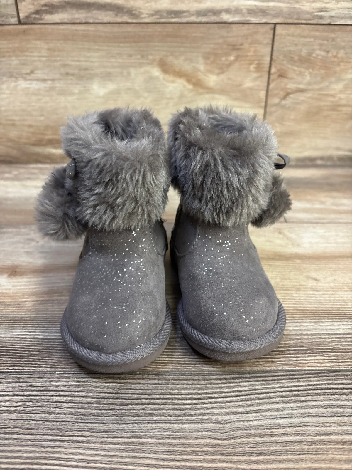 Front view of Jumping Beans toddler boots with grey suede, faux-fur cuff, and glitter speckles on wood background