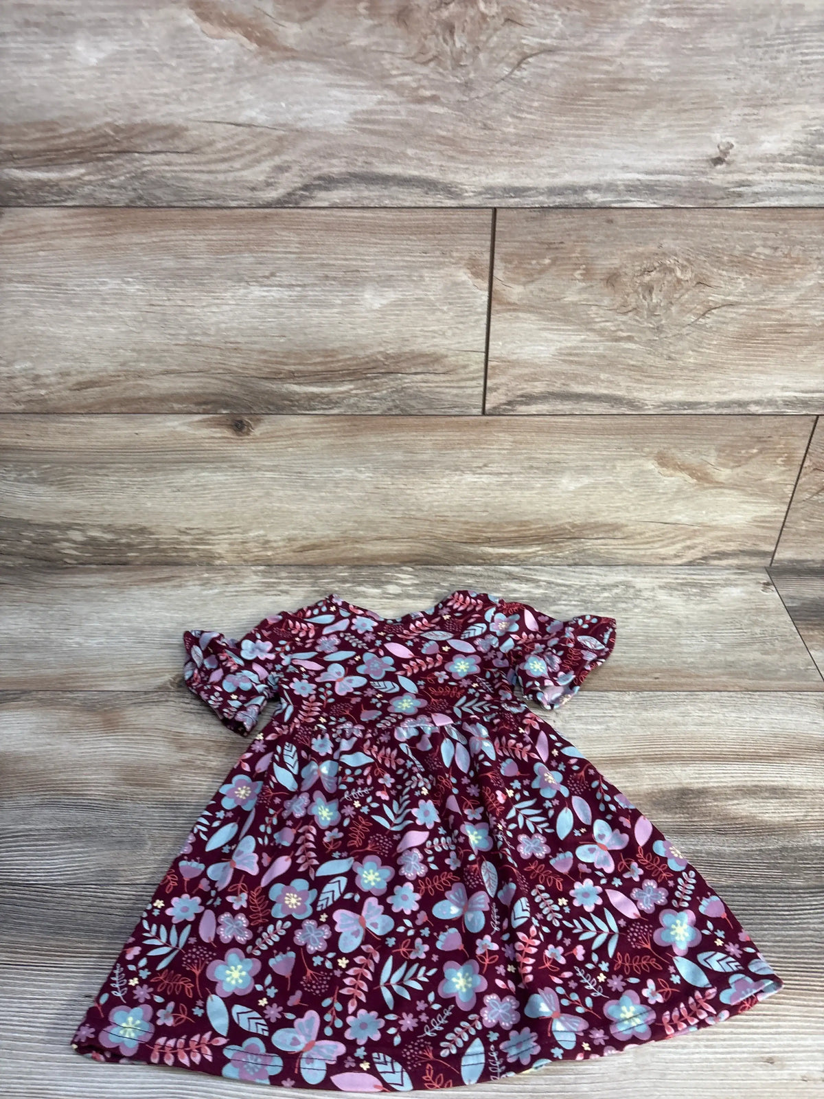 Front view of Picapino floral dress in maroon, size 12 months, showcasing its delicate floral print on a wood-look floor