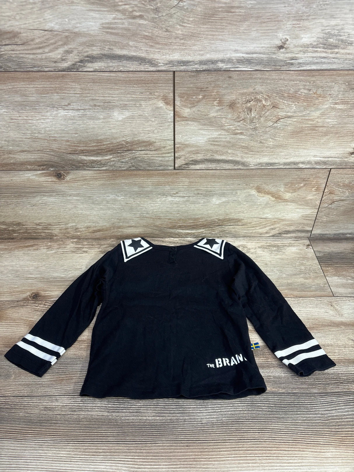 Black long sleeve toddler shirt with star shoulder accents and white stripes on sleeves