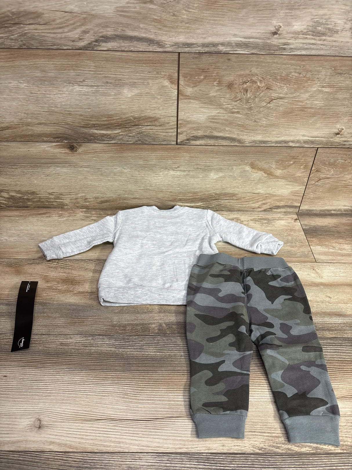 Gray long sleeve toddler shirt with green camo pants set on wooden background