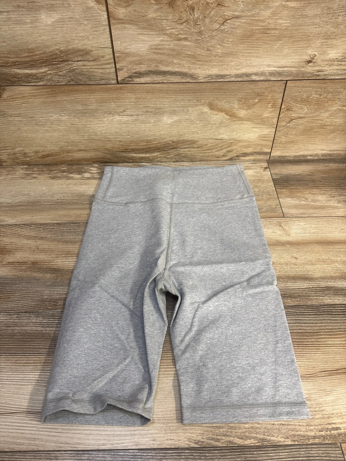 Front view of grey New Gap maternity bike shorts showcasing the smooth flat wide waistband on a wood look floor