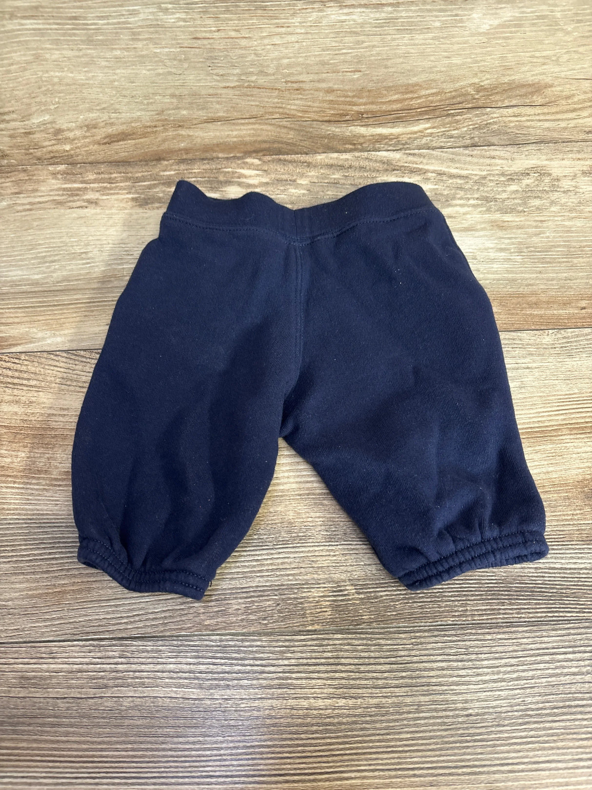 Black baby pants with elastic waistband and cuffs on wood background, gently used kids clothes
