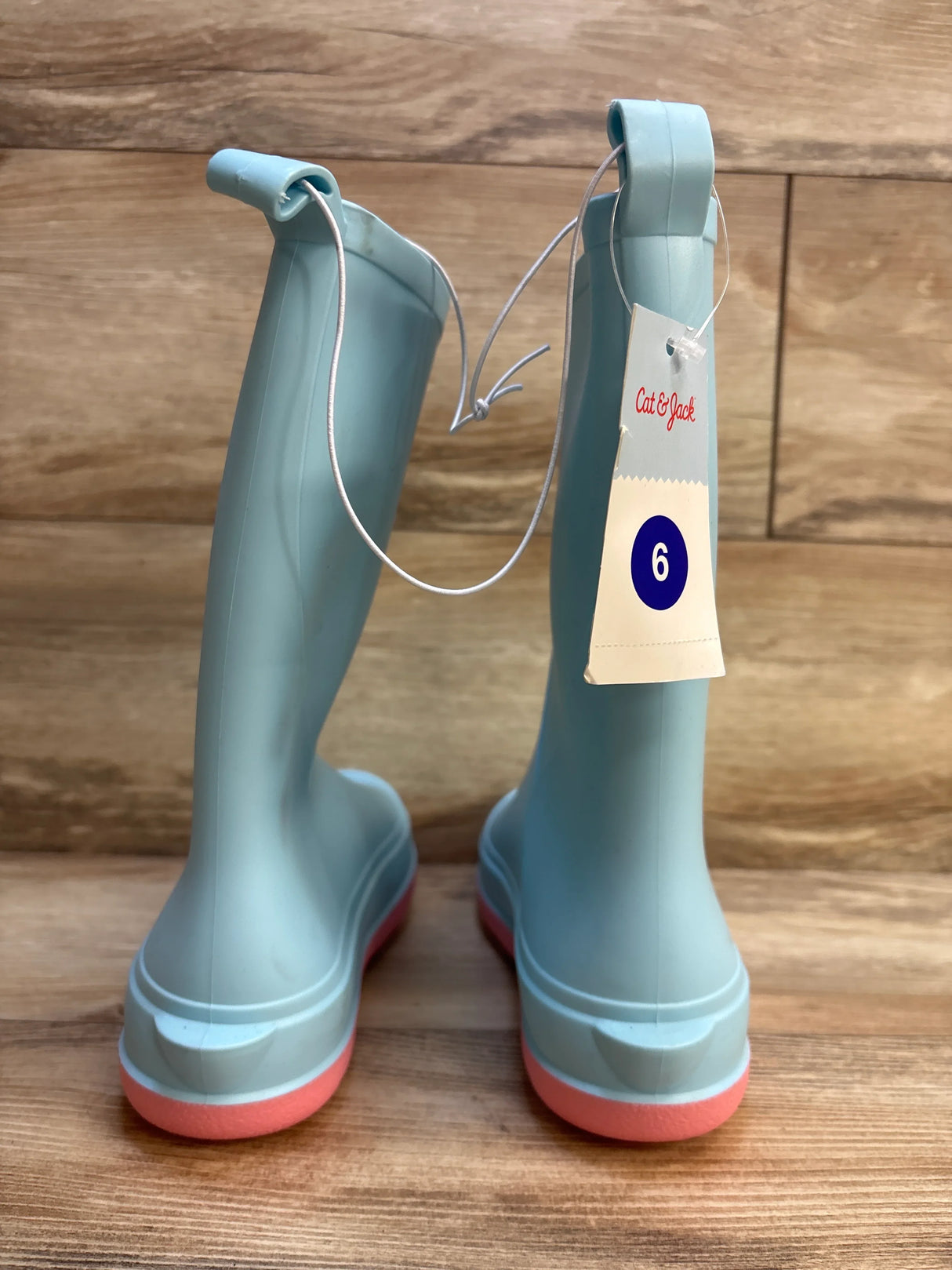 Light blue kids rain boots with pink soles, size 6, Cat & Jack brand, on wood floor
