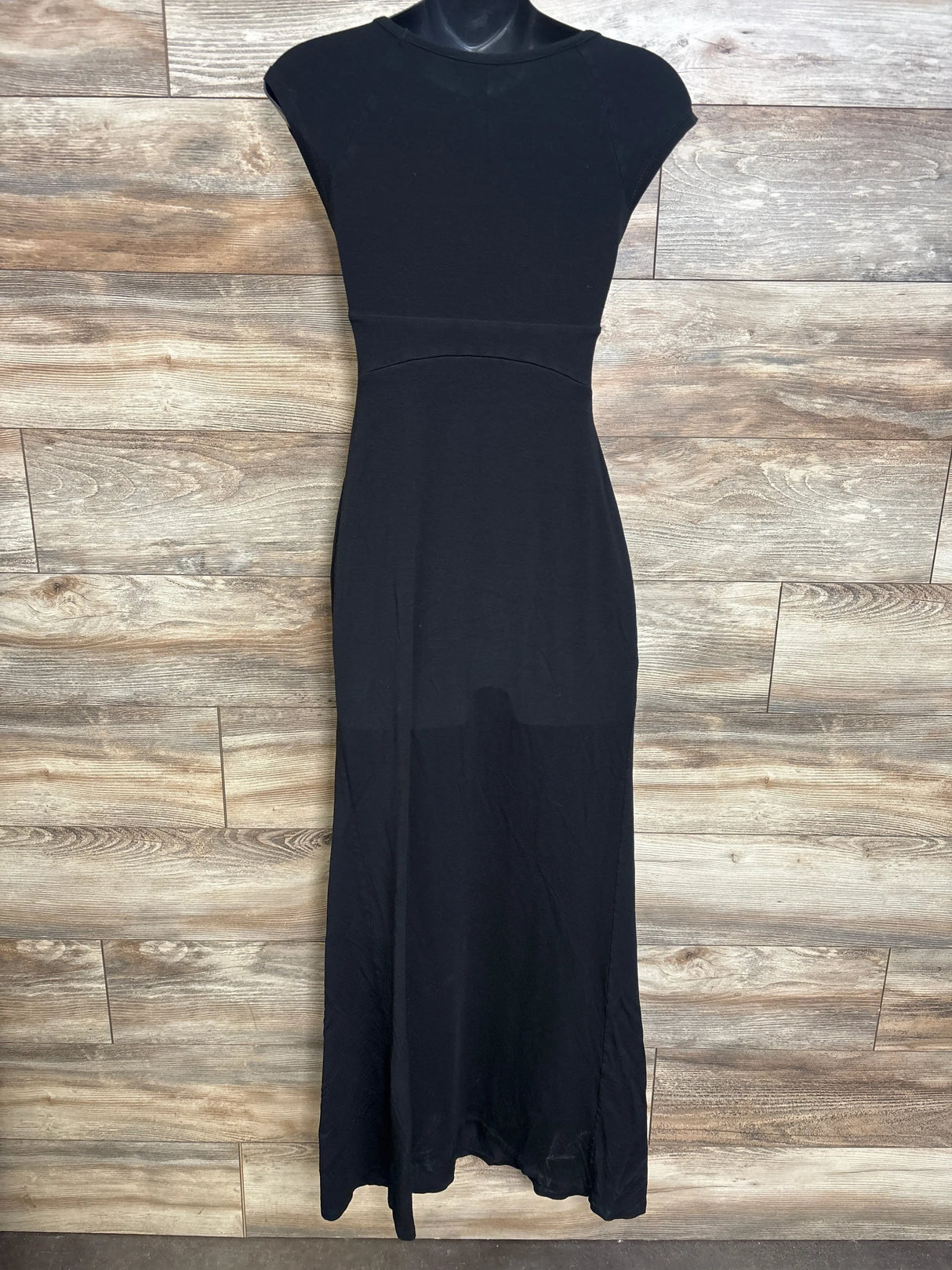 Front view of black maternity cap-sleeve maxi dress showing empire waist and long skirt on mannequin on wood background