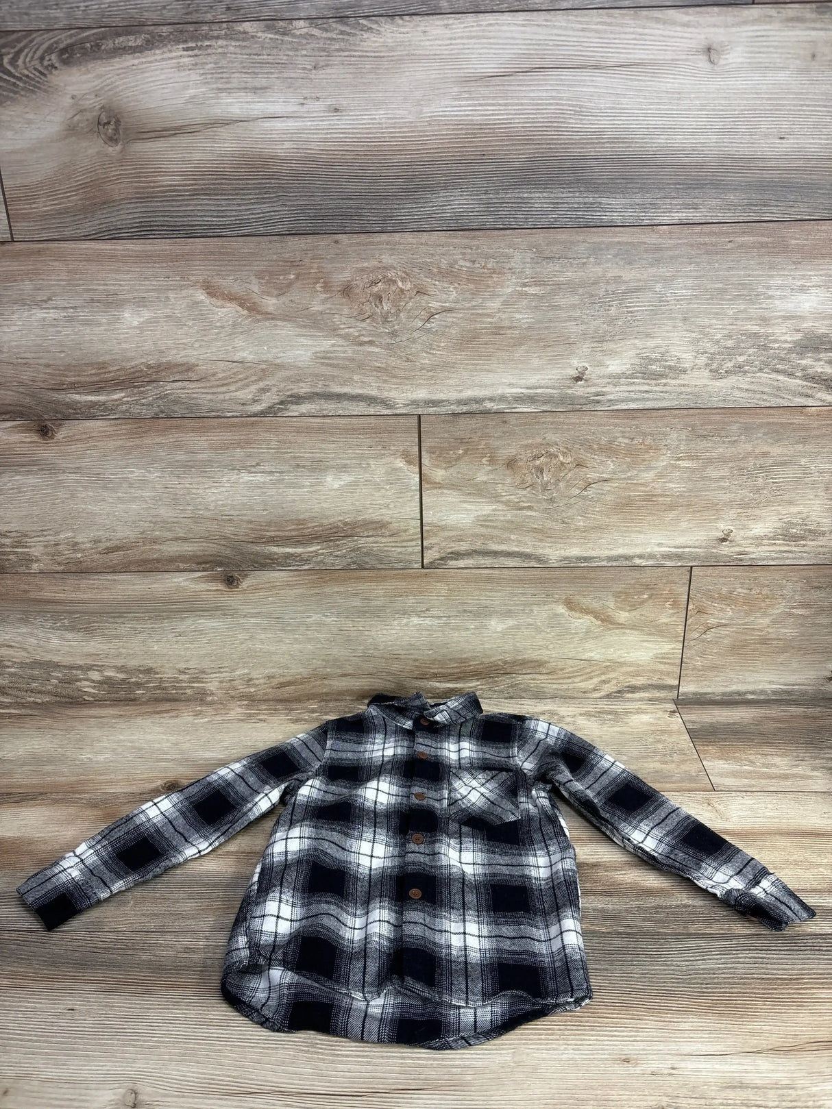Black and white plaid long-sleeve button-up kids shirt on wood background at children's resale store