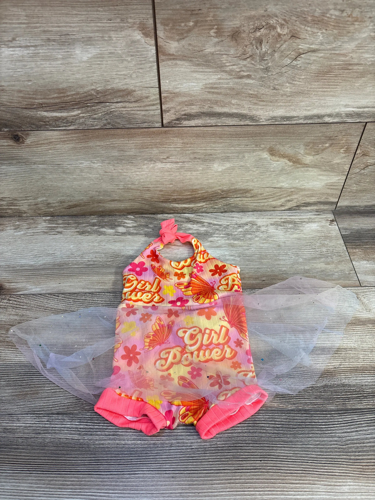Front view of pink Girl Power tulle overlay romper showcasing floral print and layered tulle on wood-look background
