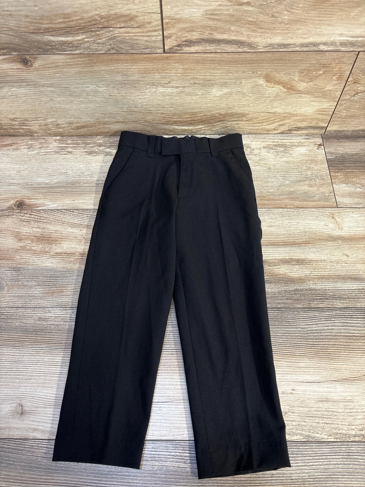 black formal trousers with belt loops laid flat on wooden floor