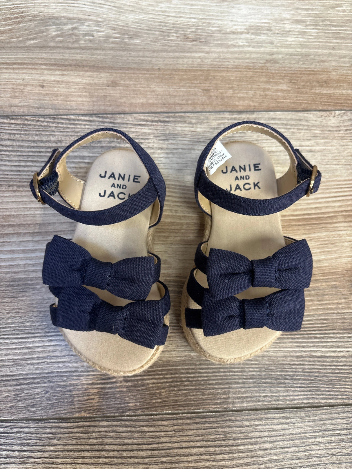 Navy blue toddler sandals with bows and ankle straps on wood background
