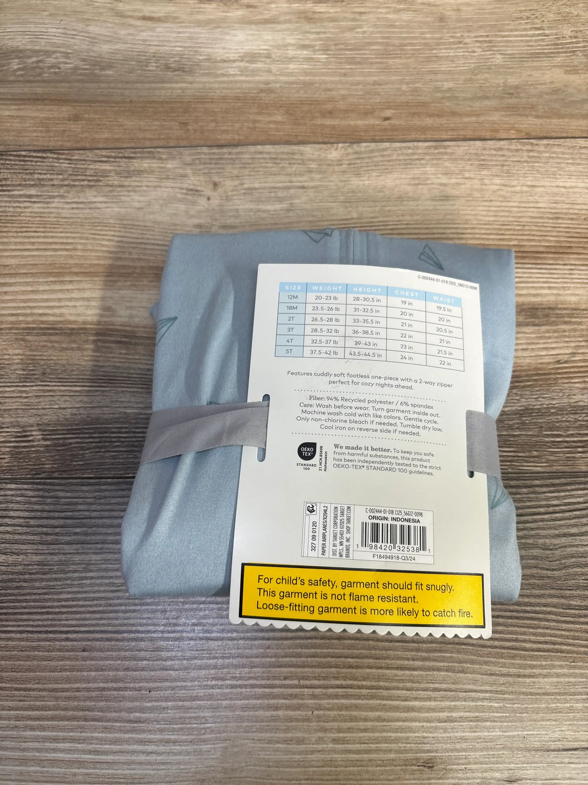 Size chart and product details on the packaging of a blue footless sleeper.