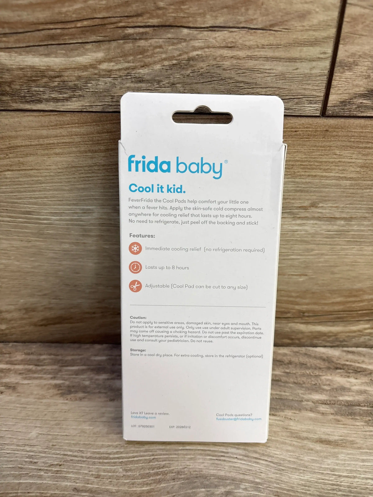 Rear view of Frida Baby FeverFrida Cool Pads 5-pack packaging showing 'frida baby' logo, 'Cool it kid' headline and features text against a wood background