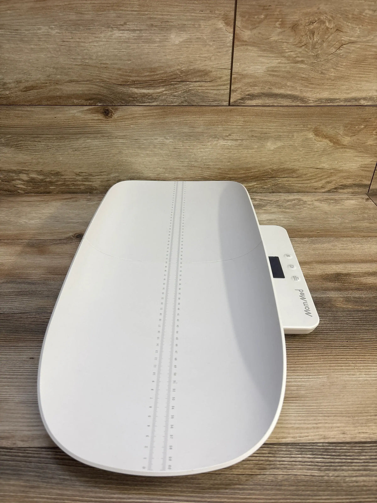 Top view of MomMed Baby Scale showcasing height measurement markings and digital display with wood-grain background