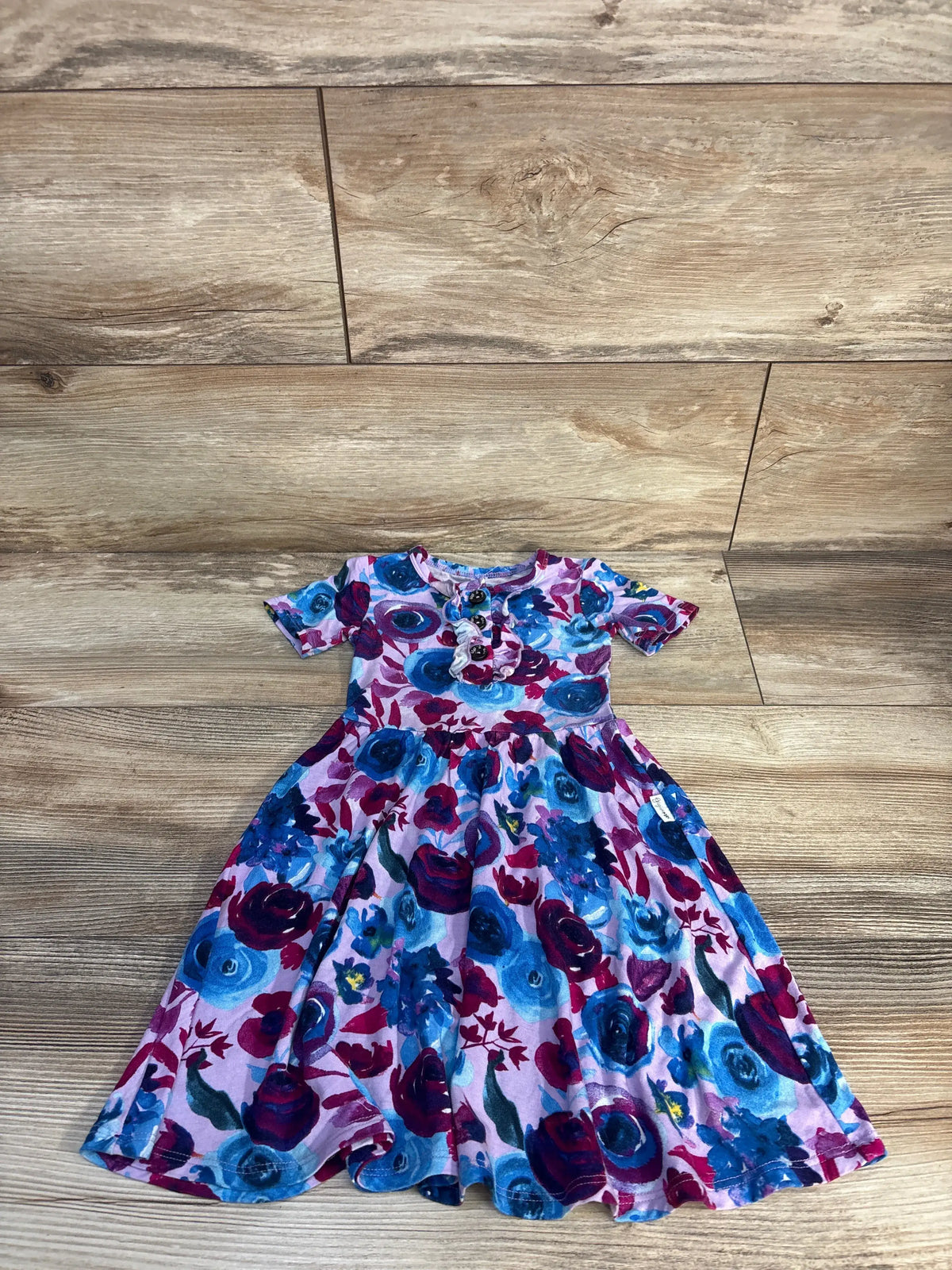 Top view of Gigi & Max purple floral bamboo tutu dress, size 2/3T, showcasing short sleeves and full skirt on a wood floor