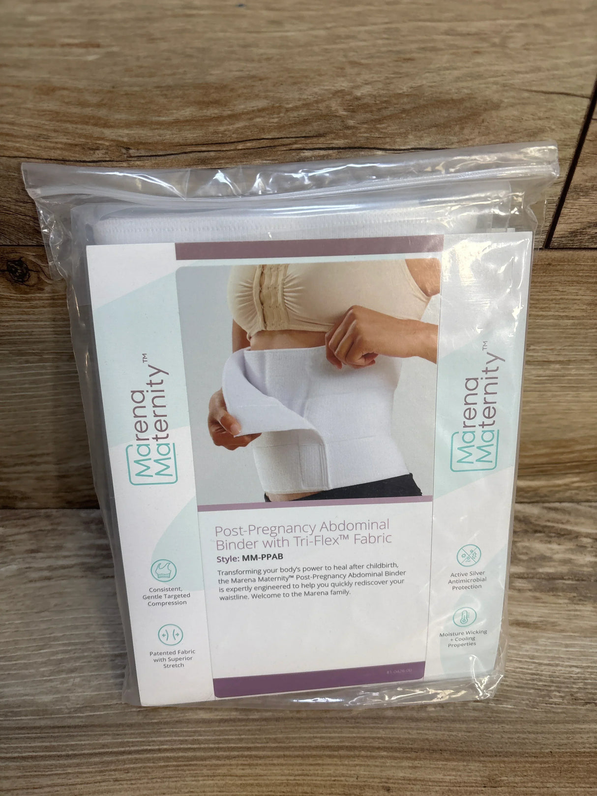 Post-pregnancy abdominal binder in packaging on wood background, maternity support belt product