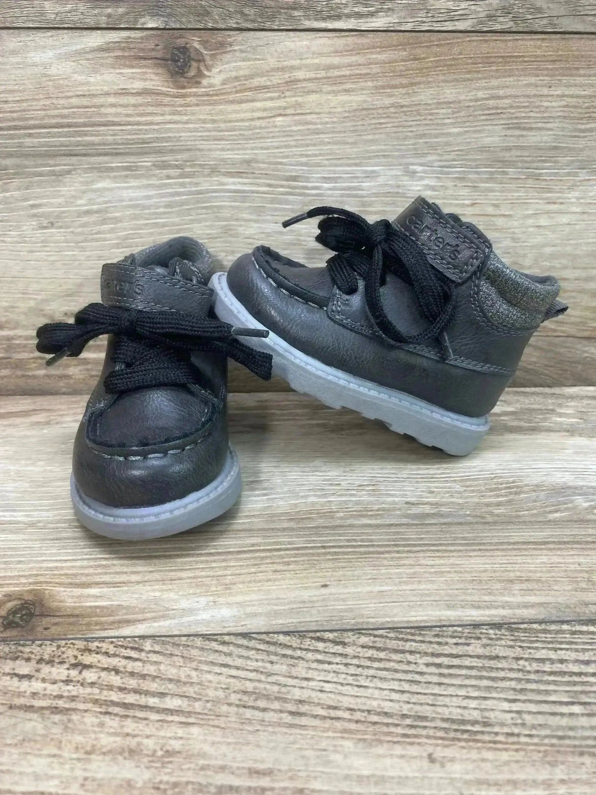 Three-quarter view of Carter’s Norman ankle boots in grey with black laces, knit cuff and translucent white sole on wood