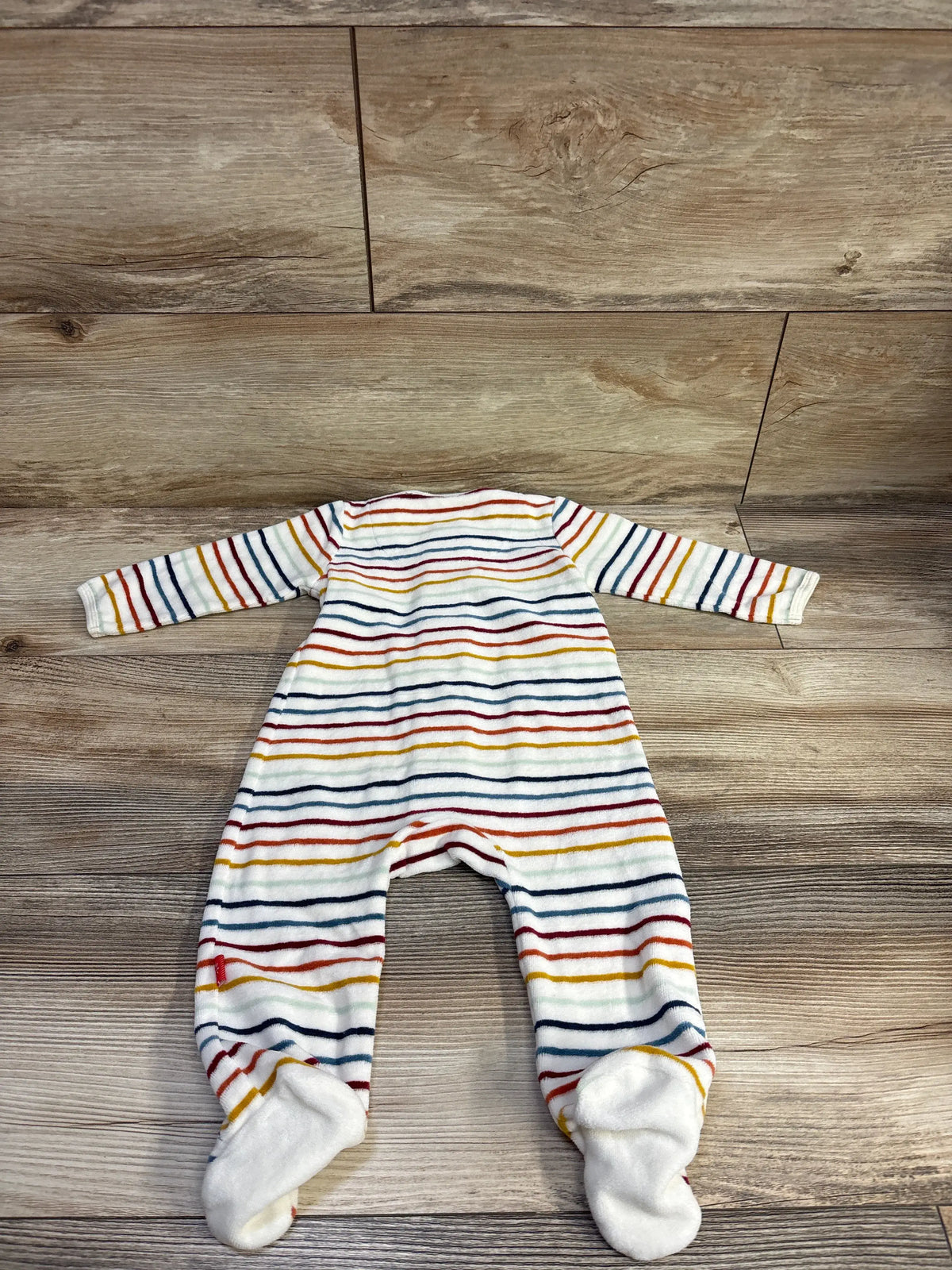 Flat lay of Magnetic Me velour footie sleeper, white with multicolor stripes, footed, long sleeves on wood background