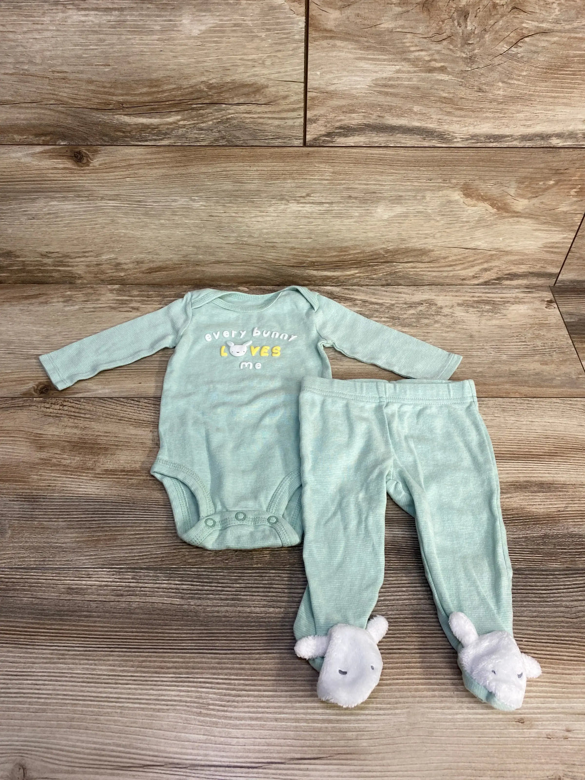 Front view of green 2-piece baby bodysuit and pants showcasing Every Bunny Loves Me bunny graphic on the bodysuit with white background