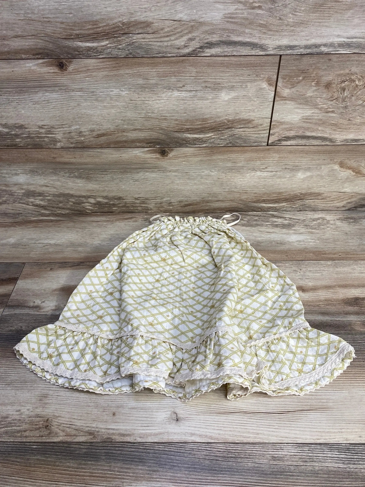 Flat lay of Liilu organic sleeveless floral dress size 4T showing yellow lattice print and ruffled hem on wood background