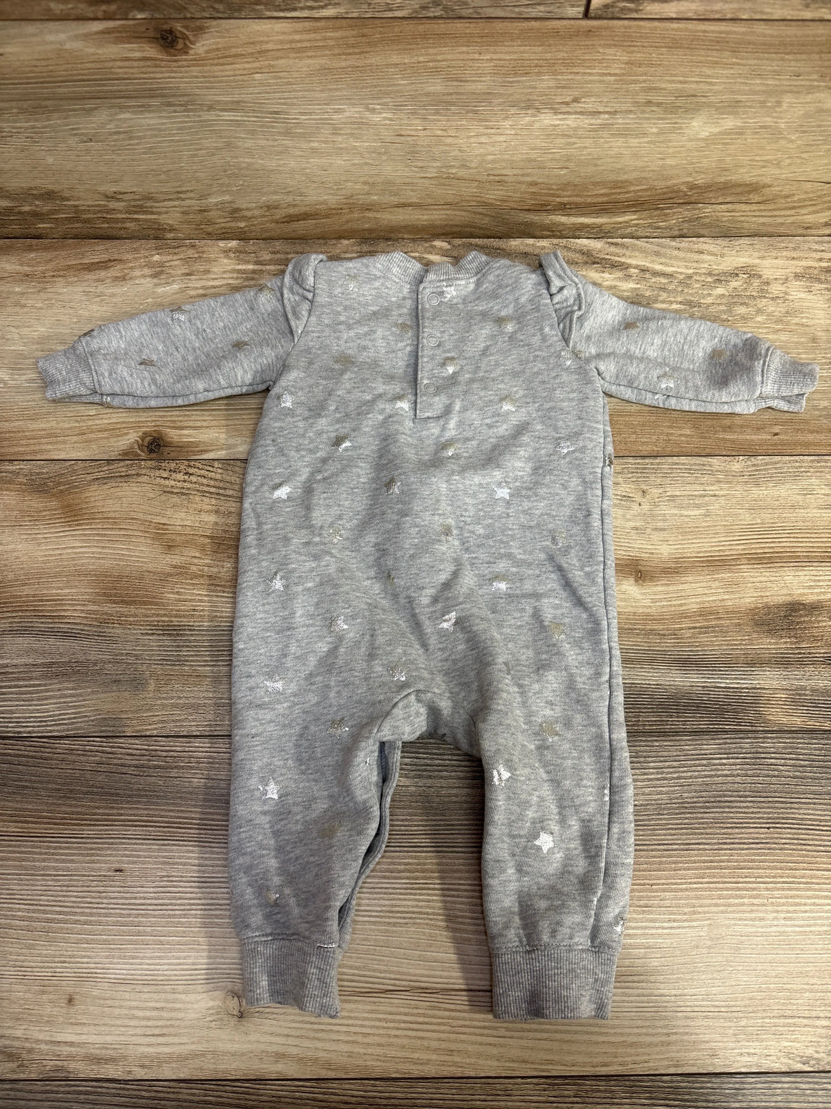 Gray long-sleeve baby romper with silver star prints on wooden floor background