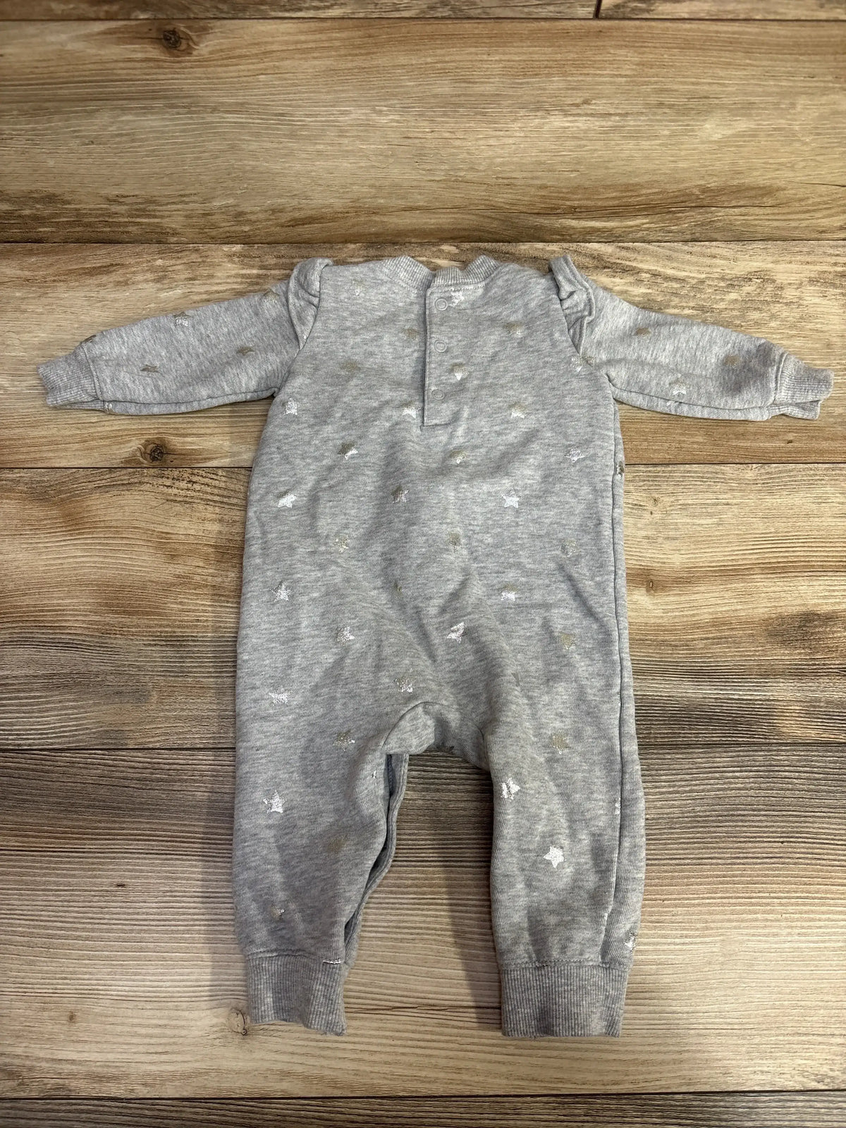 Gray long-sleeve baby romper with silver star prints on wooden floor background
