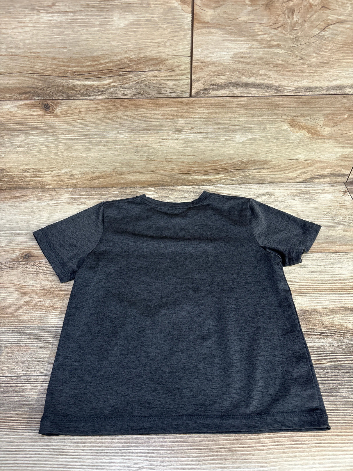 Back view of plain dark gray t-shirt on wood background, short sleeves, casual tee