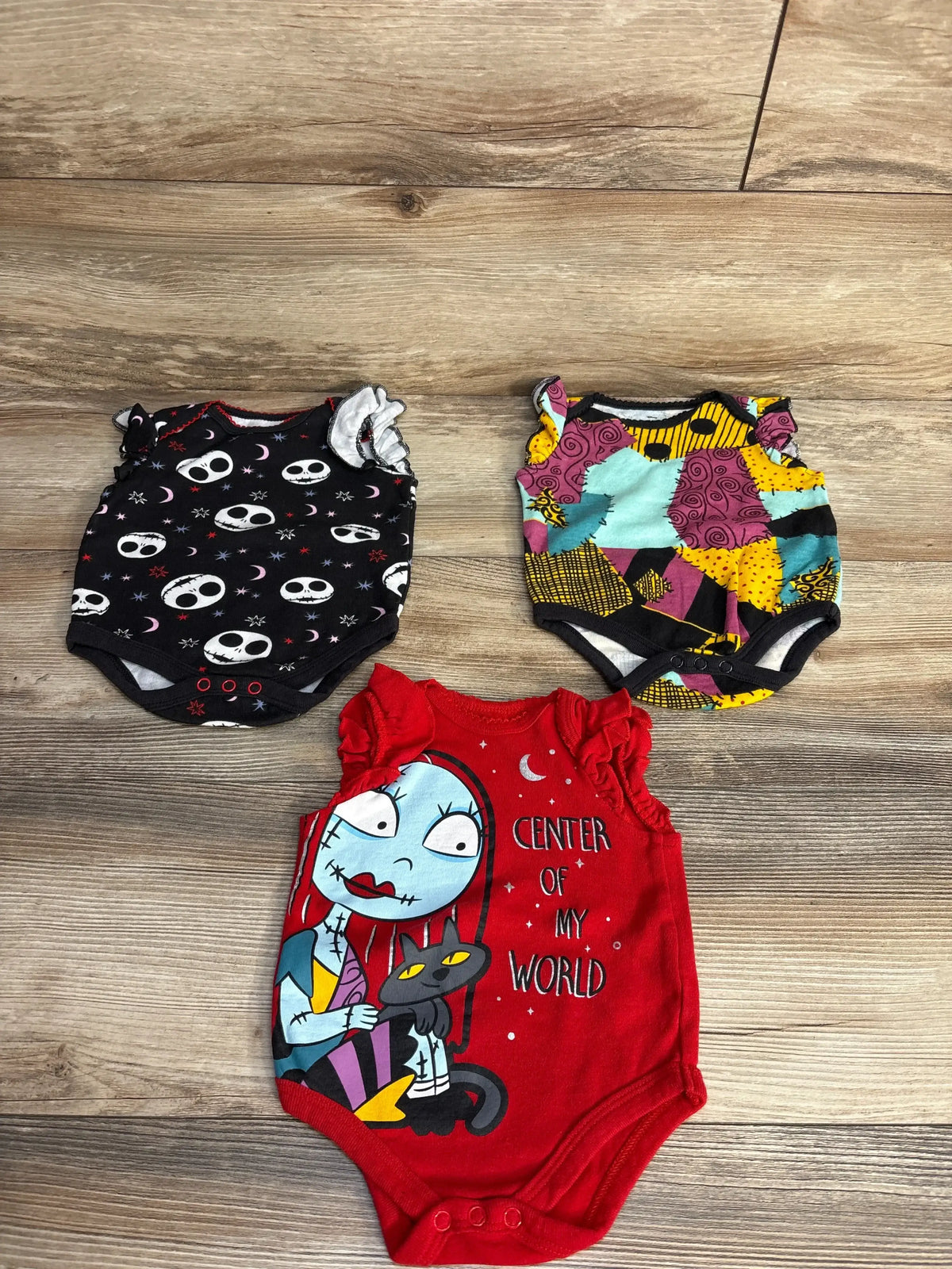 Top view of three Disney Nightmare Before Christmas bodysuits in size 0 to 3 months, including red Center of My World design