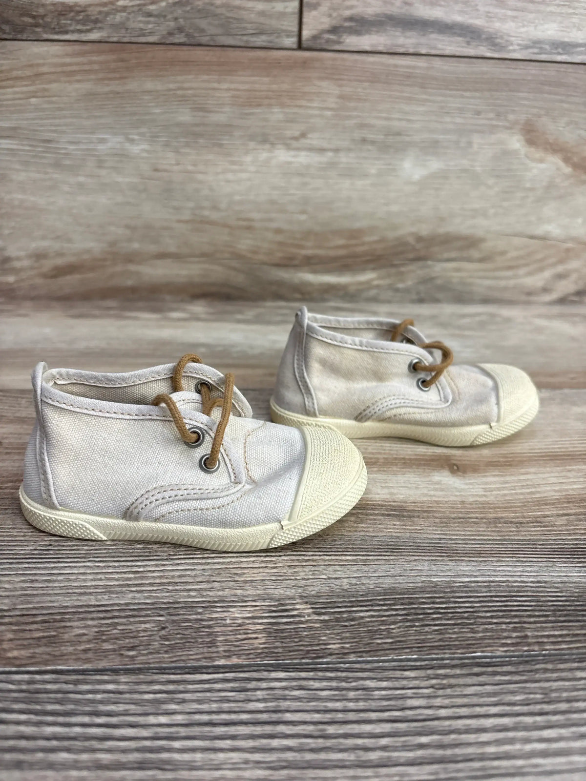 Side view of Zara beige canvas toddler sneakers size 3C showing brown laces and rubber toe caps on wooden floor