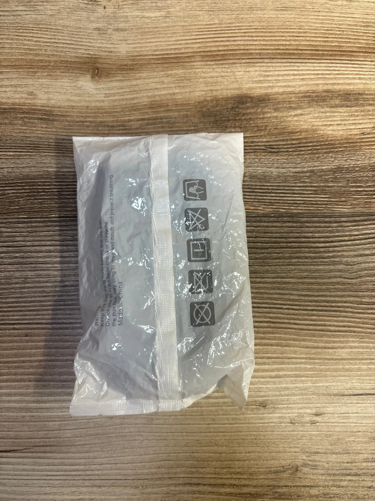 Top view of NEW Baby Knee Pads, Navy showcasing the clear plastic package on a wood-grain surface