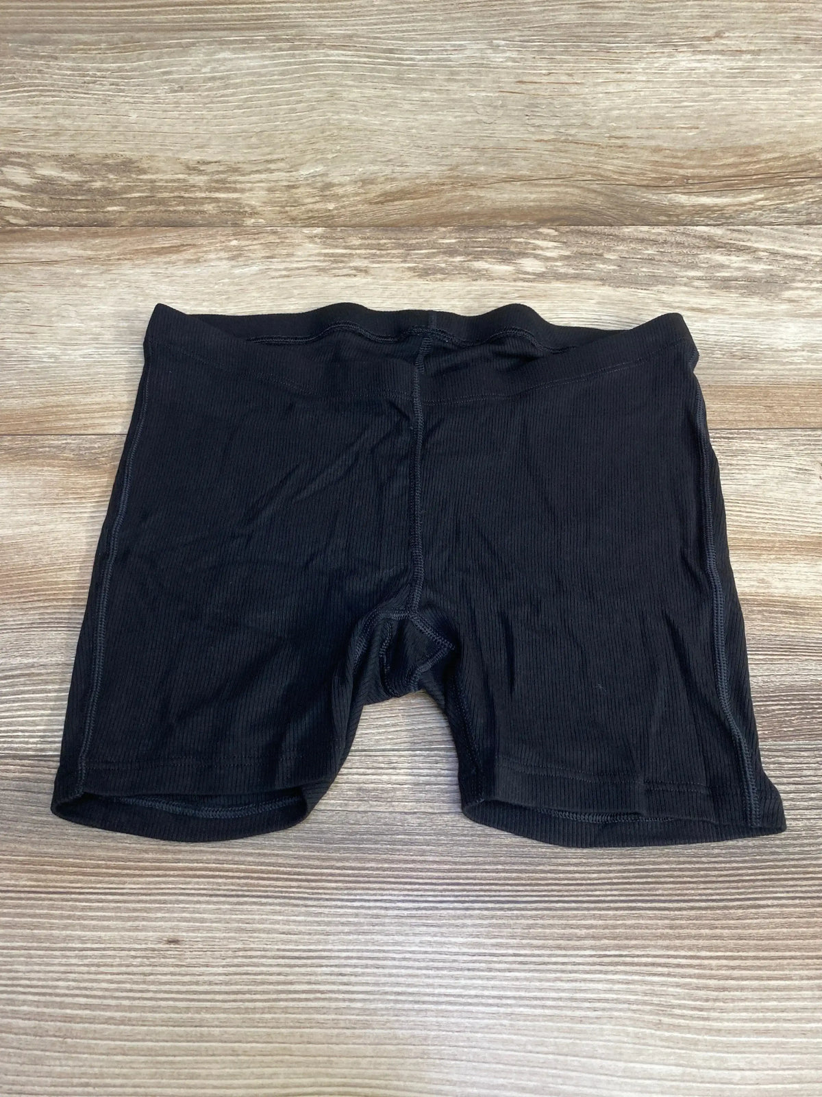 Front flat lay of black Gap maternity rib PJ shorts showing elastic maternity waistband and ribbed fabric on wood background