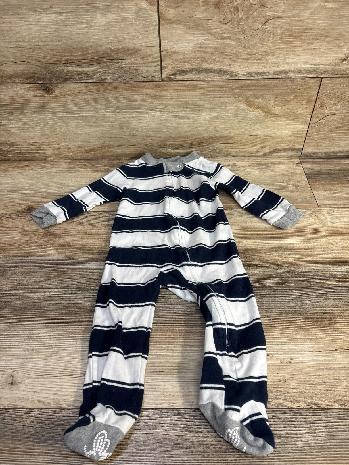 Flat lay of Burt's Bees Baby sleeper 6-9 months, navy and white stripes, front zipper, gray grippy feet on wood