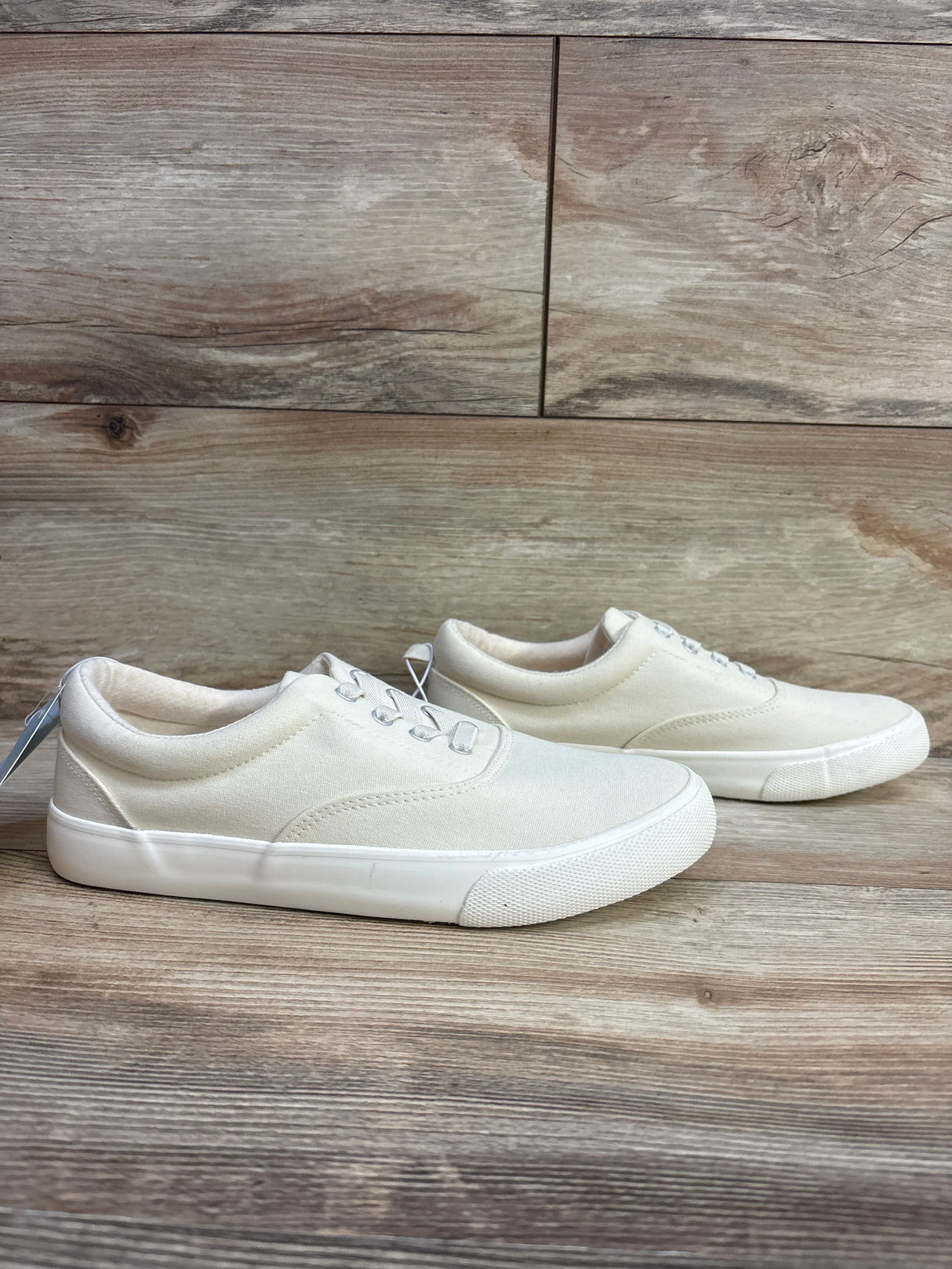 Kids white canvas sneakers with rubber soles on wood background