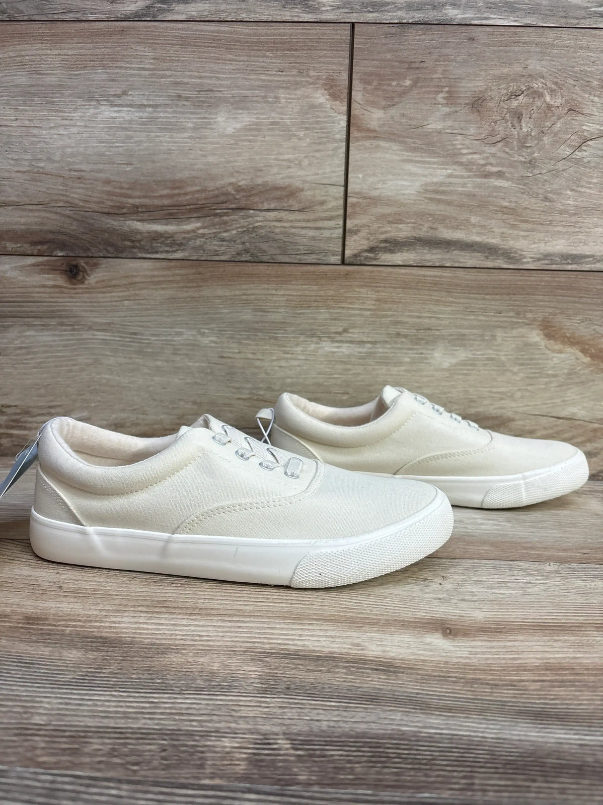 Three-quarter view of Cat and Jack Tyler off-white canvas slip-on sneakers with white rubber sole on wood plank background