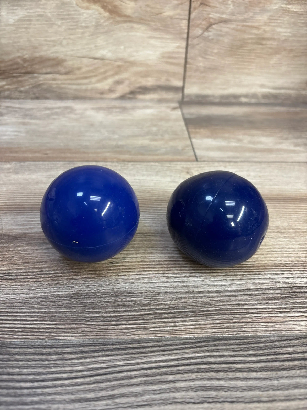 Front view of Lovevery Opposite Balls showcasing two dark blue spheres on a wood-grain surface