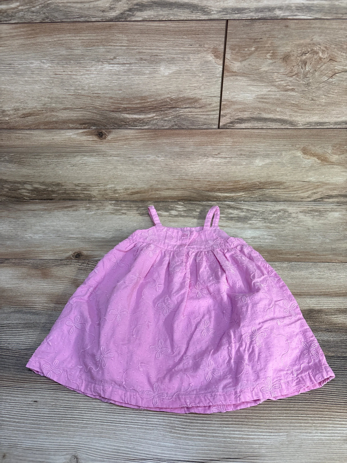 Flat lay of Baby Gap pink embroidered dress 18 to 24 months showing floral eyelet embroidery, gathered bodice and thin shoulder straps on wood background