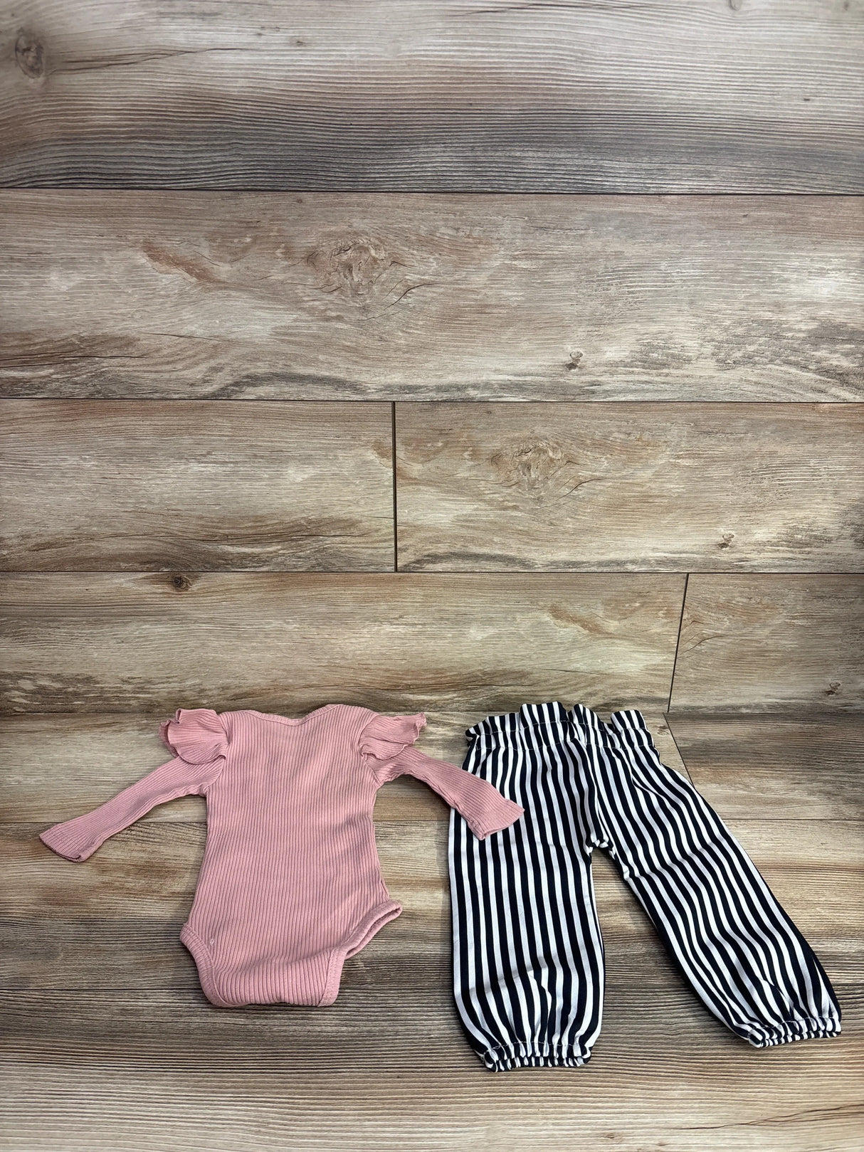 Pink long sleeve baby bodysuit with ruffle shoulders and black and white striped pants