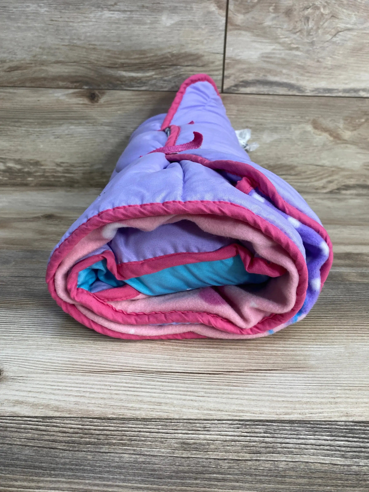 Rolled view of Funhouse Unicorn kids nap mat showing unicorn print and attached carry strap on white background