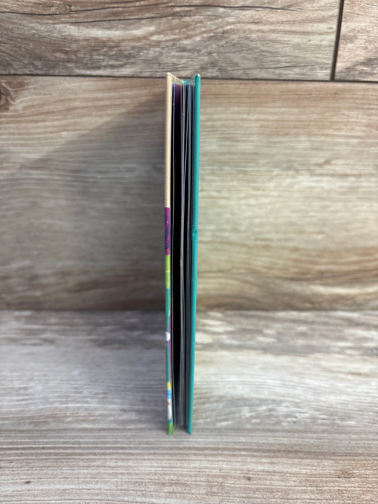 Two thin colorful hardcover books standing vertically on a wooden surface