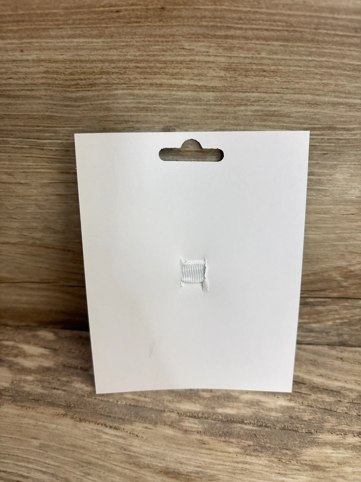 Front of empty white display card for NEW Layered Crown Glitter Hair Bow showcasing stitched ribbon holder with wood background