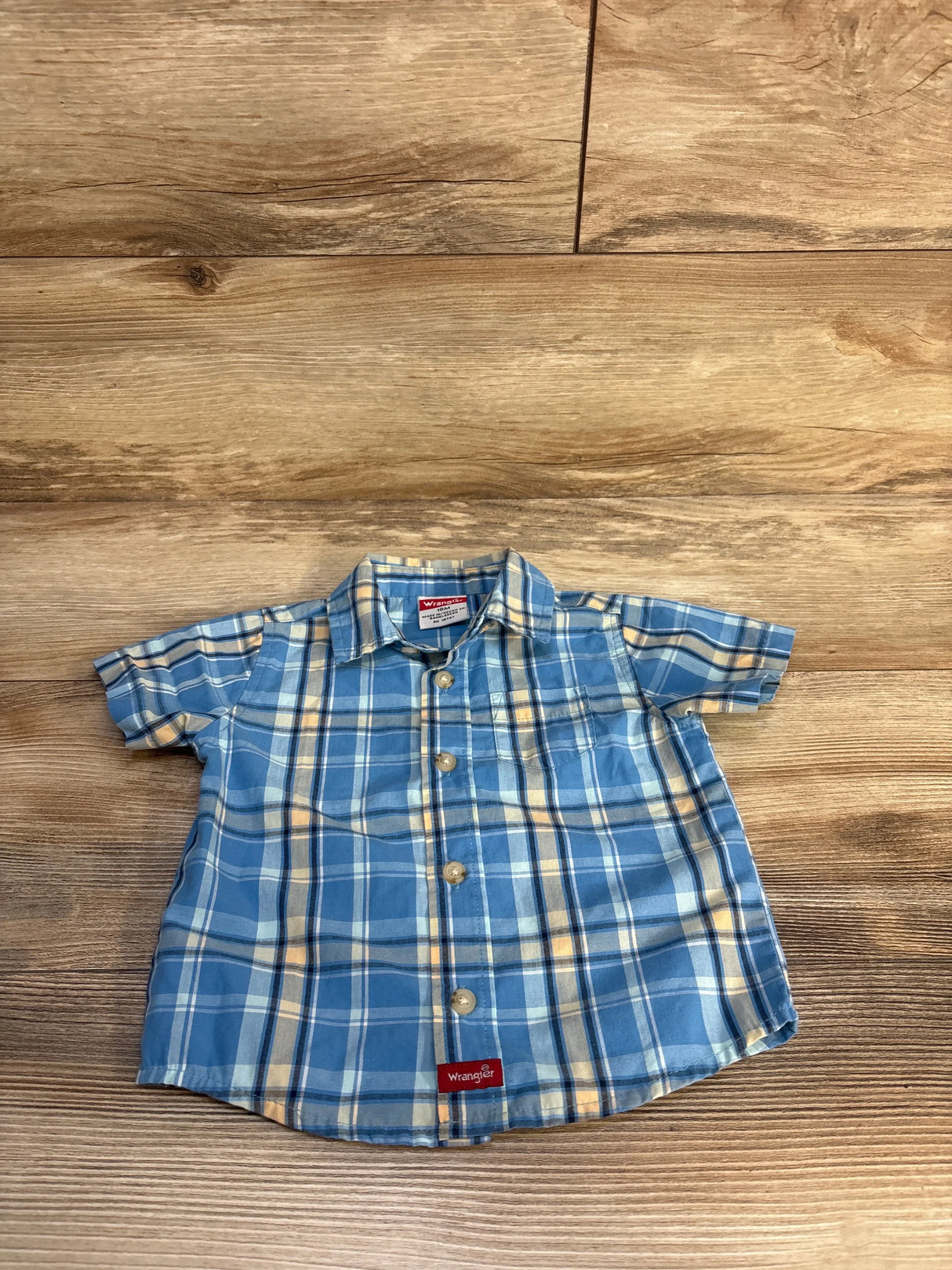Blue and yellow plaid short sleeve toddler button-up shirt on wood background